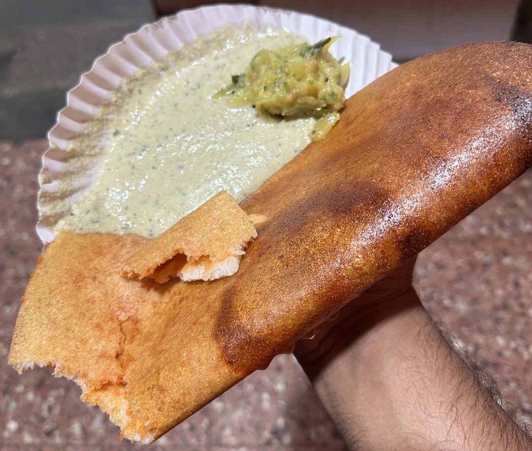 Me holding a plate of Mysore masala dosa right outside Vaibhav Food Canopy, Mysore.